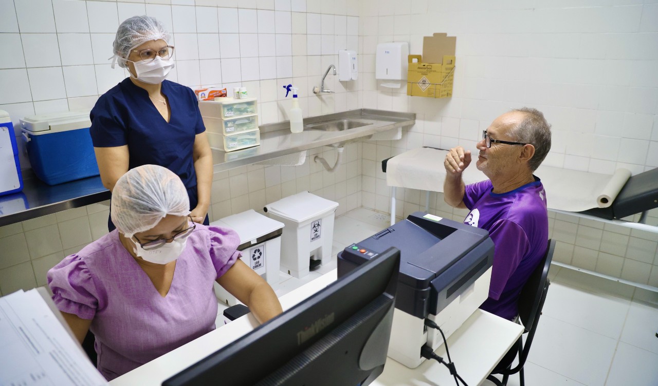 medica e enfermeira conversam com um senhor em um consultório de posto de saúde